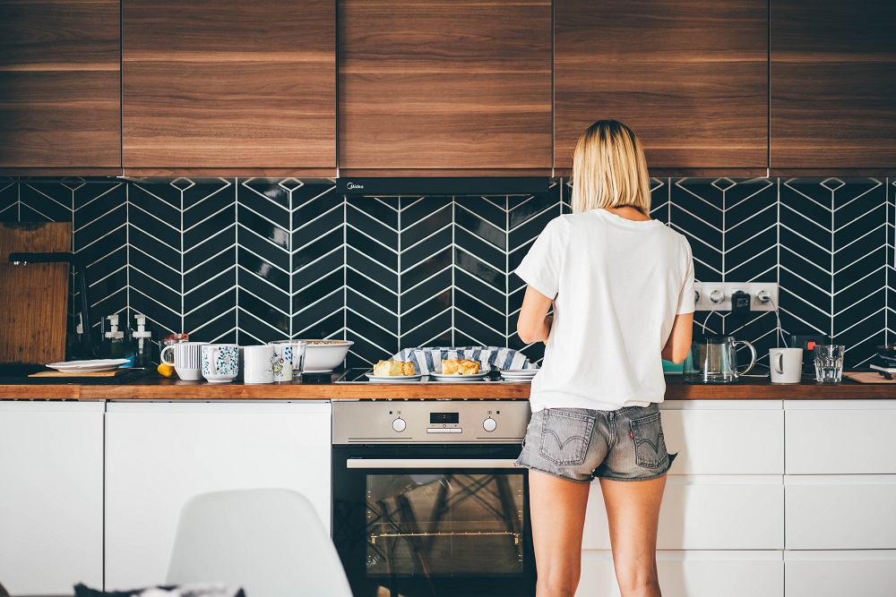 A woman modernizing a black and white tiled kitchen.