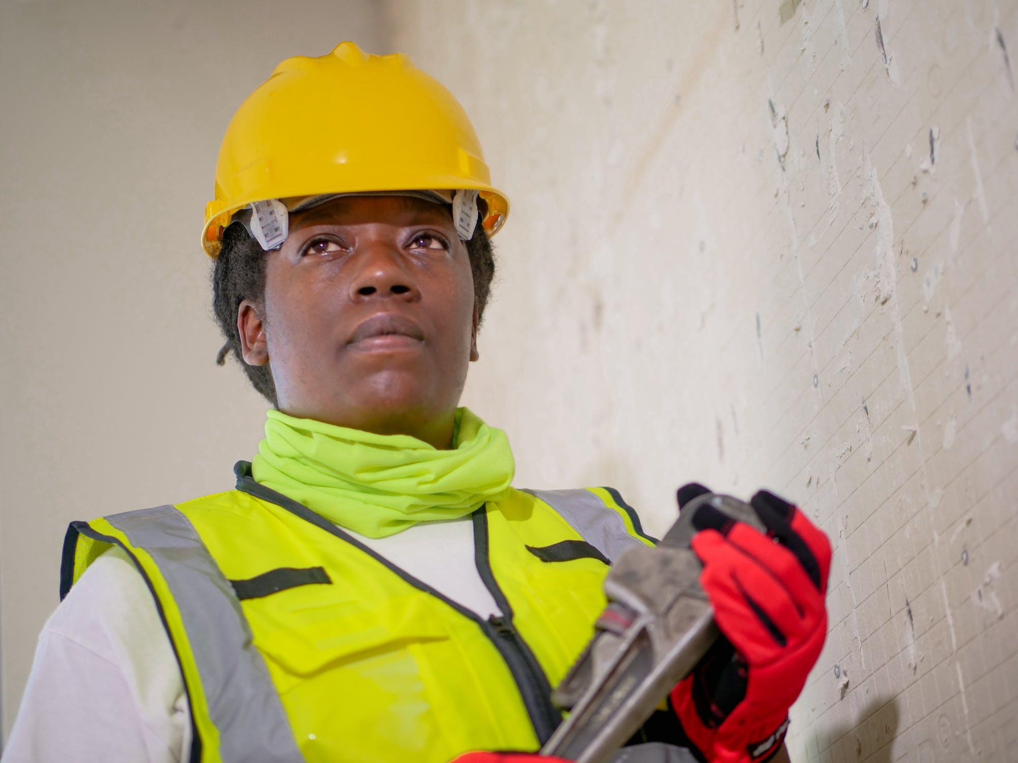 A construction worker learning a trade, wearing a hard hat and safety vest.