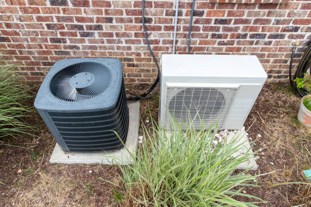 Two air conditioners: Central vs. Ductless AC Systems in front of a brick wall.