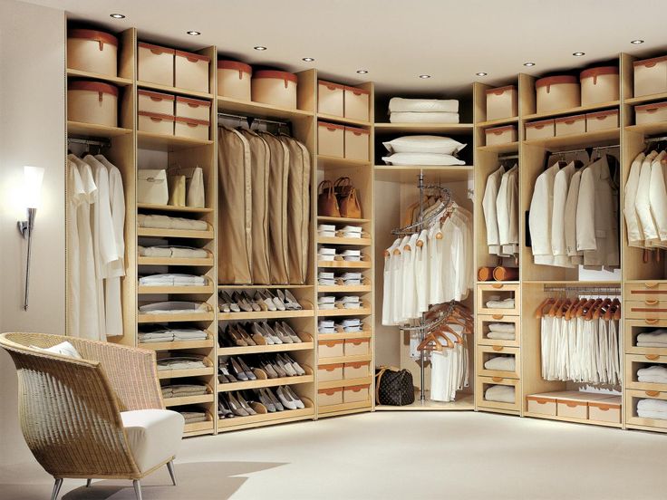 A custom walk-in closet with lots of clothes and a chair.