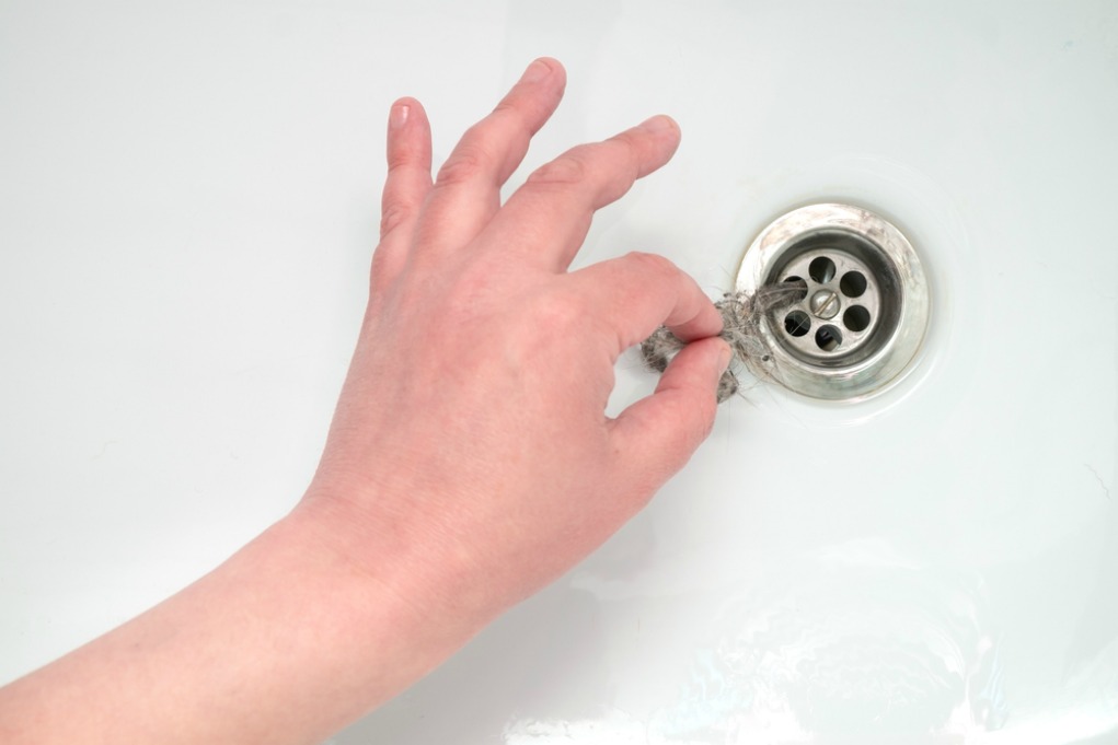 A hand holding a drain in a sink might indicate a blocked drain.