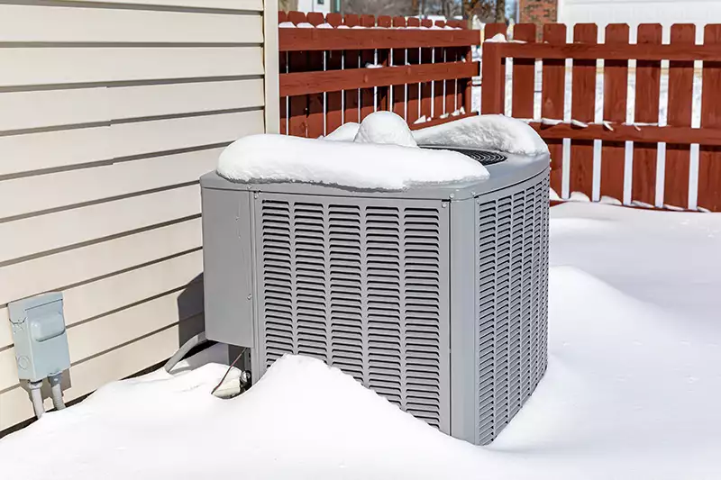 An outside AC covered in snow.