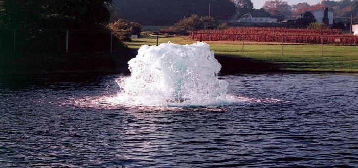 A water fountain providing aeration in the middle of a pond.