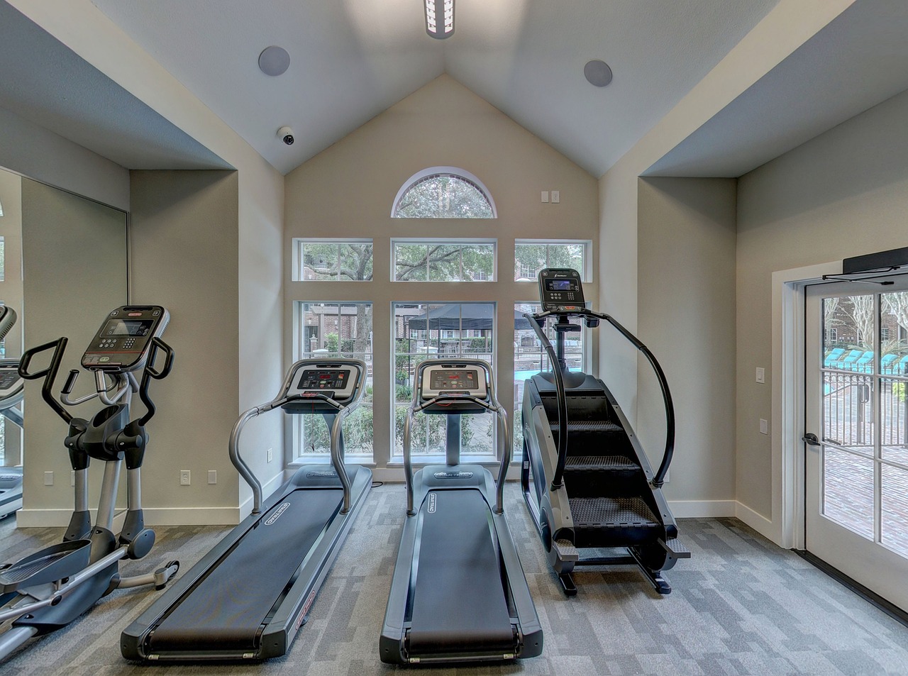 A gym with tread machines and windows: Home gym with tread machines.