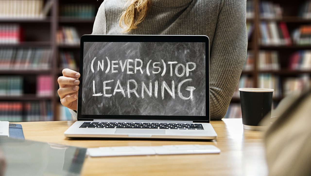 A woman holding a laptop with the word "never stop learning" on it, inspired to Learn Something New For 2023.