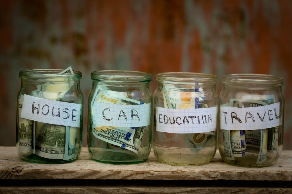 Three jars for saving money designated for house, car, education and travel.