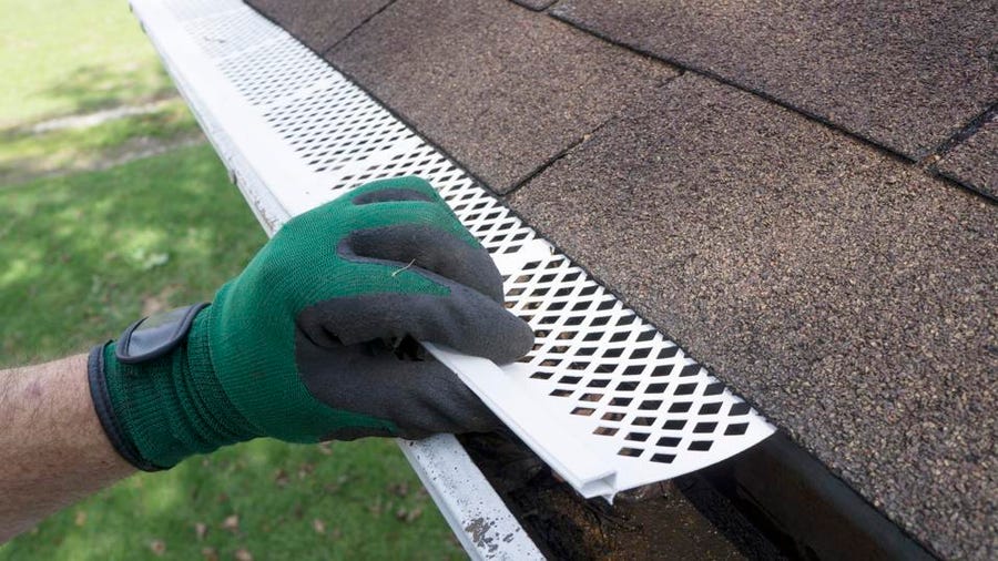 Why Does Your Gutter Need a Leaf Guard? A hand is holding a gutter grate.