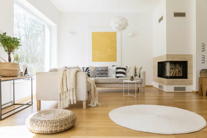 A white living room with wooden floors and a fireplace, embodying the benefits of a streamlined interior.