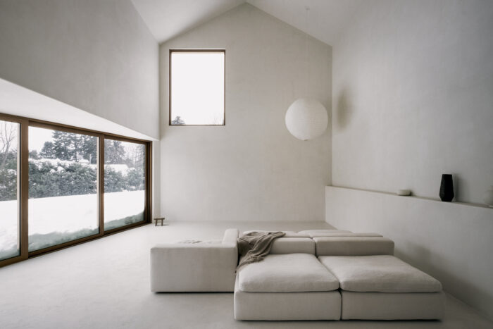 A white room with large windows and a couch that exemplifies the art of minimalism.