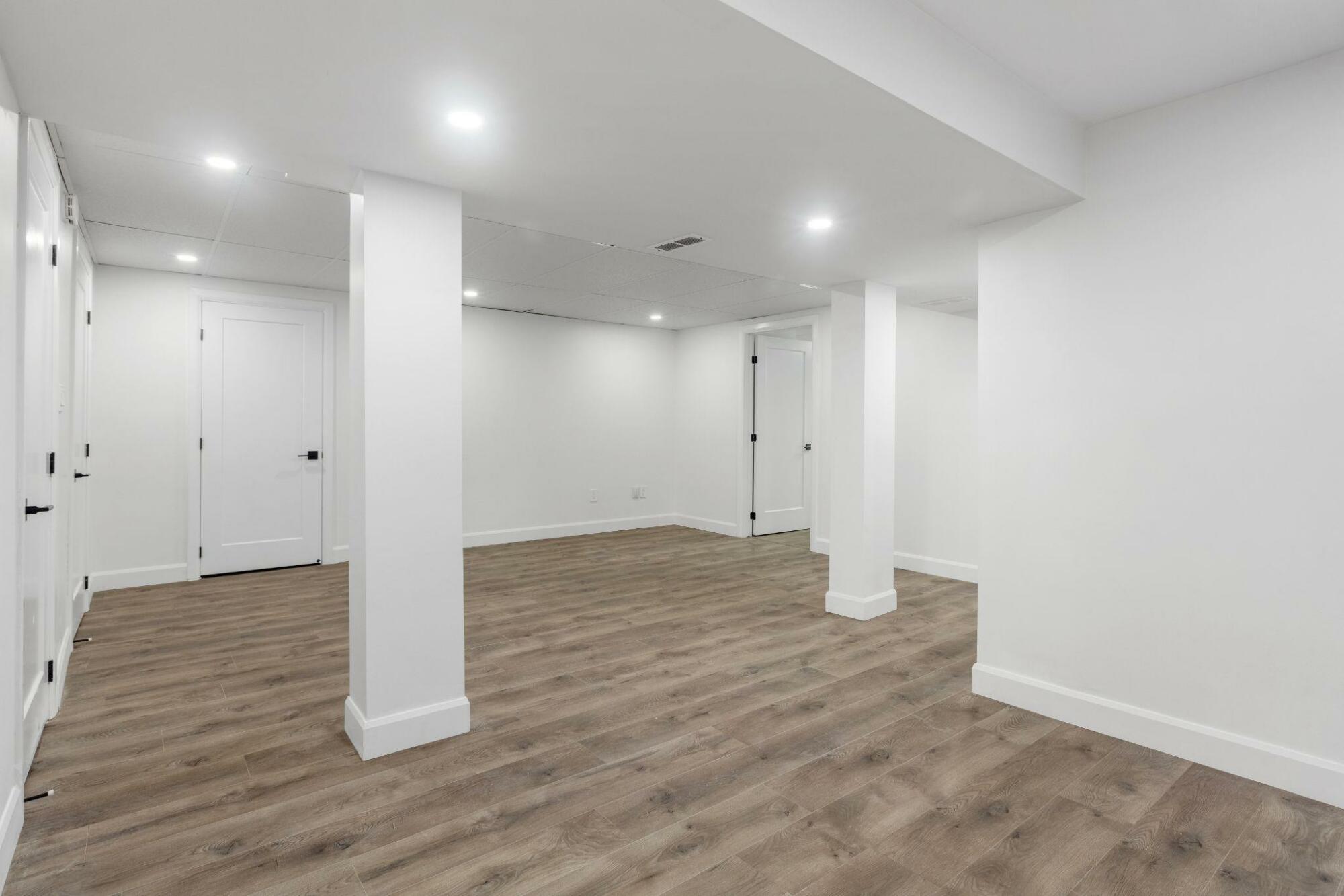 An empty basement with underpinning and hardwood floors.