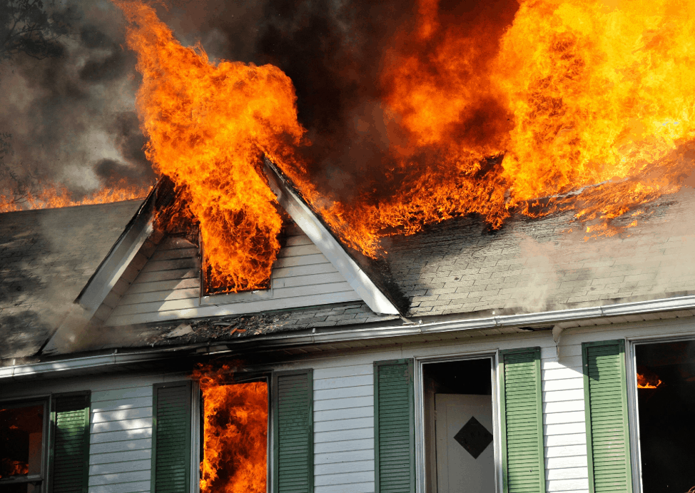 An insurance claim for fire damage to a house with flames coming out of the roof.