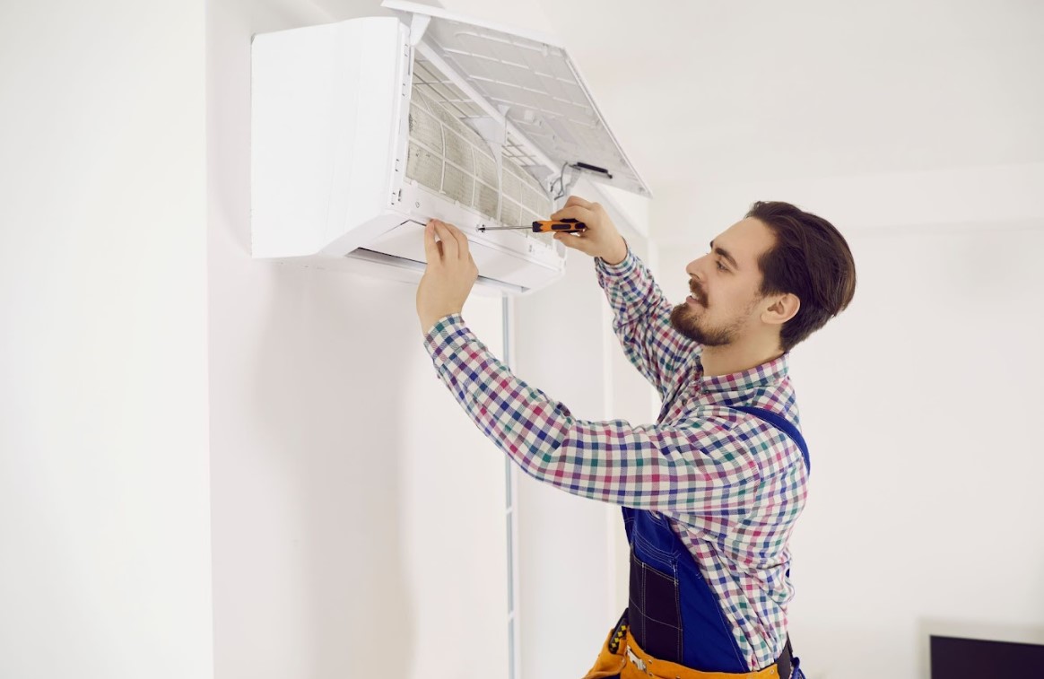 A man extending the lifespan of an air conditioner in a room.