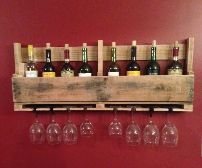 A wooden wine rack with wine glasses hanging on it, showcasing wood pallet ideas.