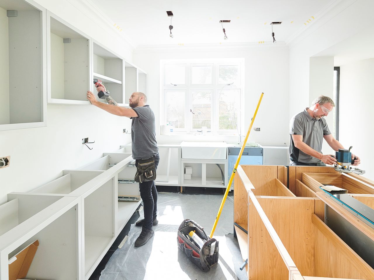 Two men sharing tips and tricks while renovating a kitchen in a new home.