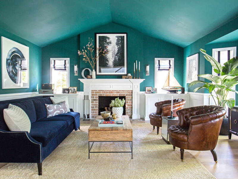 A 70's-inspired living room with teal walls and blue furniture.
