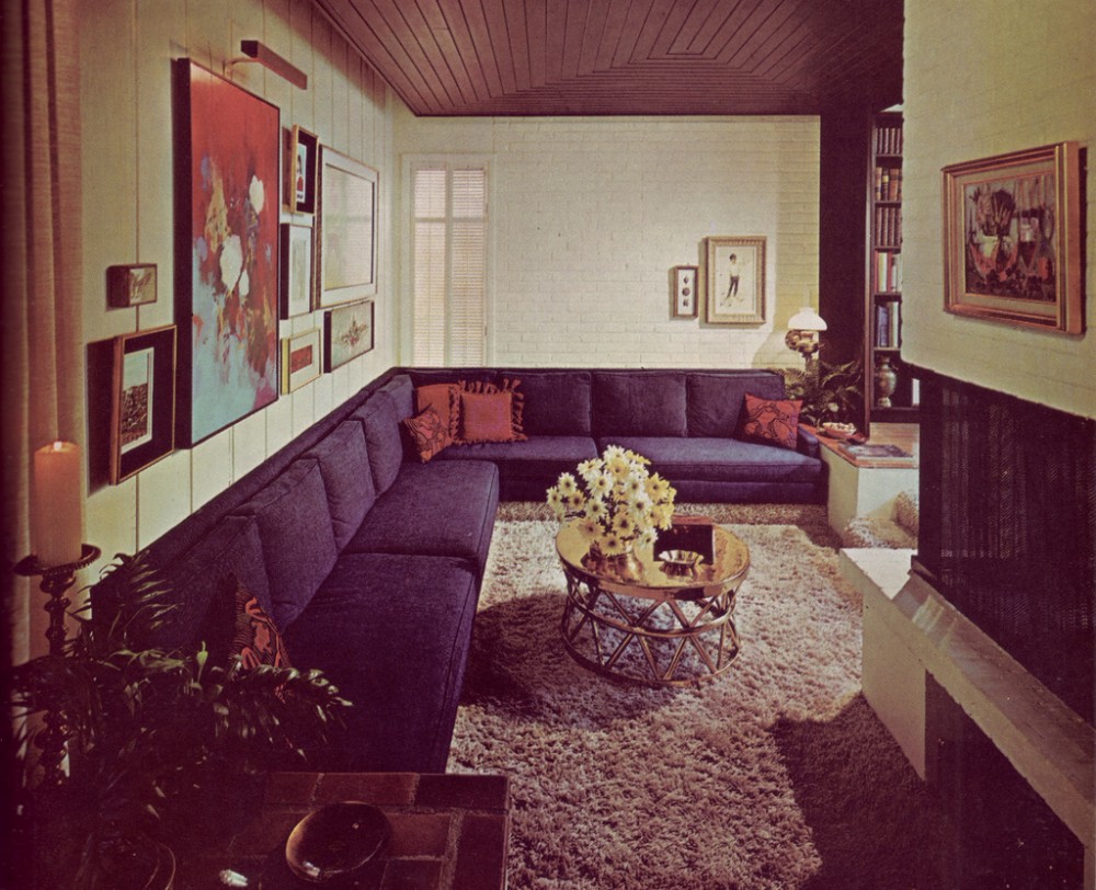 A living room with a couch and a fireplace featuring 70's interior design.