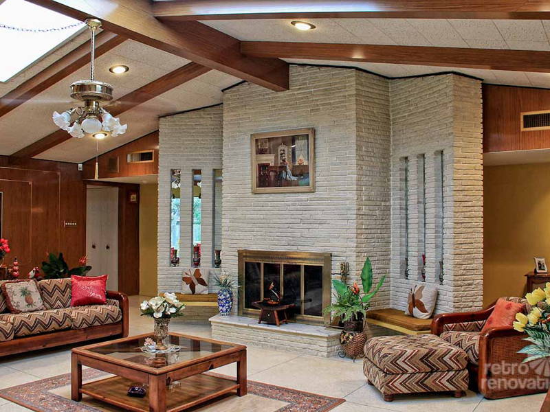 A living room with a fireplace featuring 70's interior design.