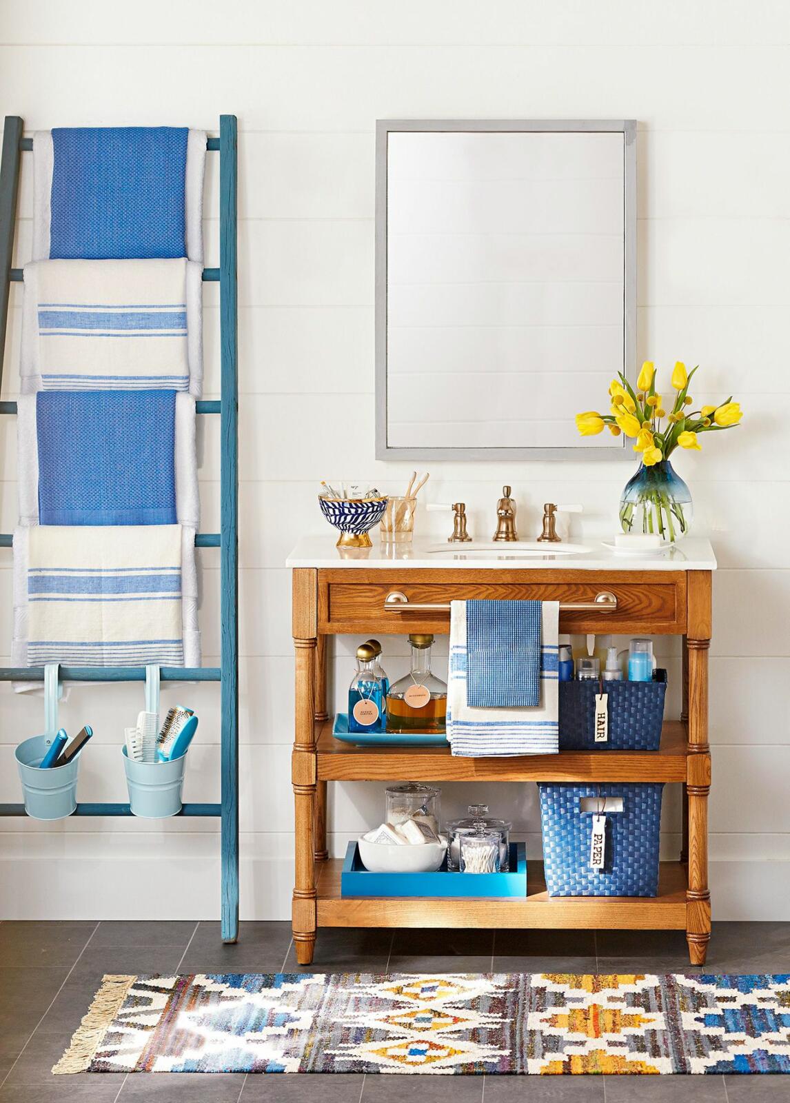 A bathroom with storage options: ladder, towels, and a rug.