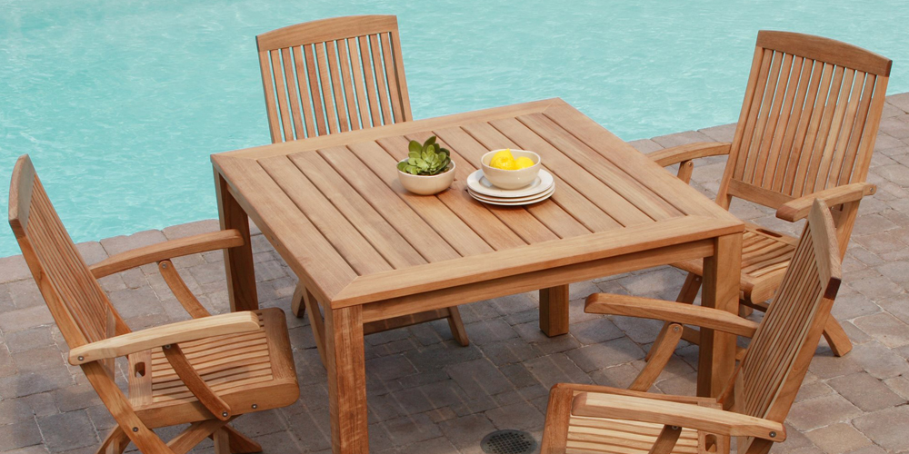 A teak dining table and chairs by the pool, perfect for outdoor use.