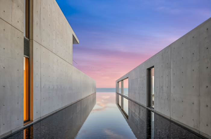 A concrete building with a reflection in the water is Beyoncé and Jay-Z's Record-Breaking California Mansion: An Architectural Marvel.
