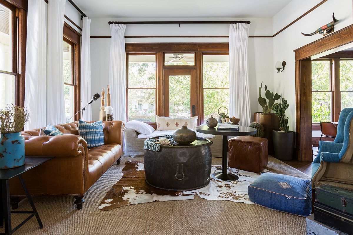 A living room with brown leather furniture and a cowhide rug embellished with a boho wall hanger.