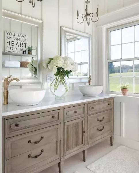 A white French country bathroom with two sinks and a mirror.