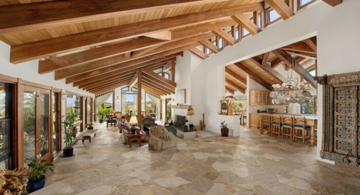 A large living room with wood beams and a fireplace, part of James Cameron's California retreat.