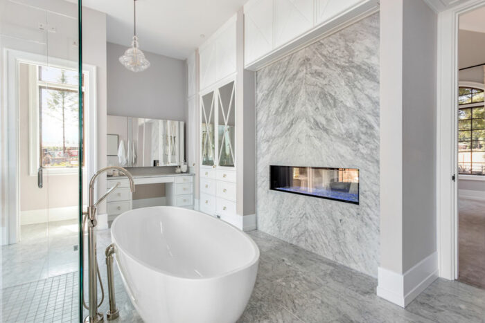 A bathroom with marble slab walls and a fireplace.