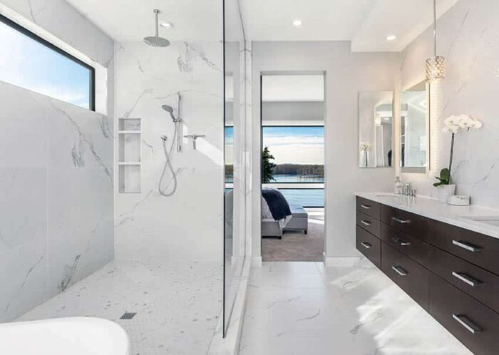 A modern bathroom with marble floors and slab shower walls.