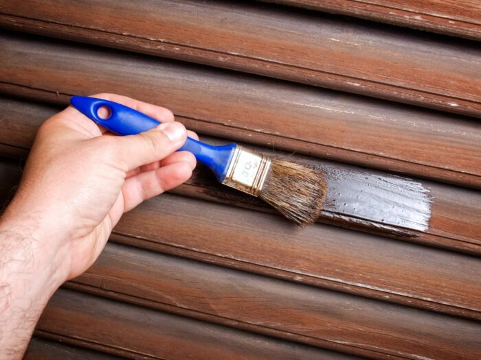 A person painting vinyl shutters with a brush