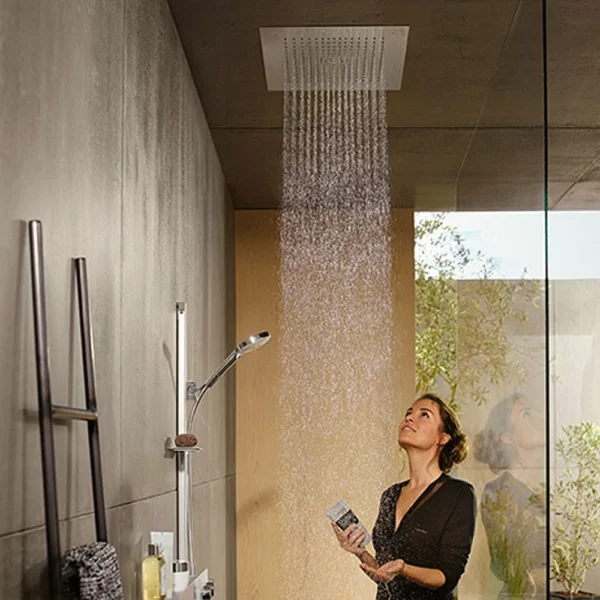 A person standing under a ceiling-mounted rainfall shower head