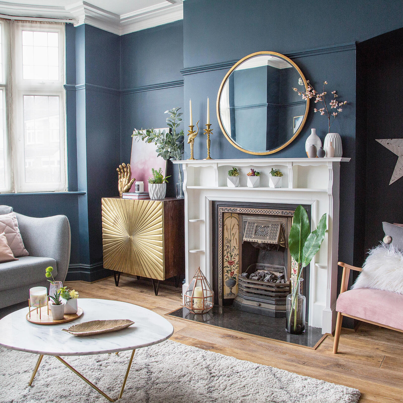 A living room with blue walls and gold accents featuring mantel decor.