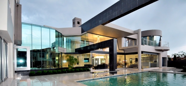 A modern mansion with glass walls and a swimming pool.