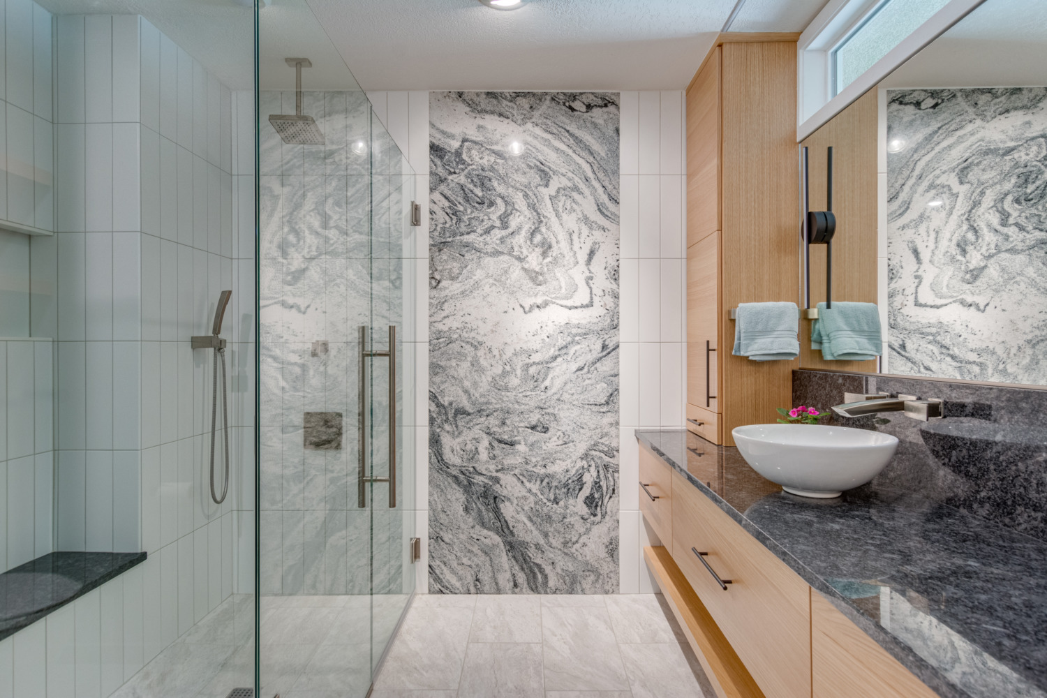 A bathroom with marble counter tops and a glass shower.