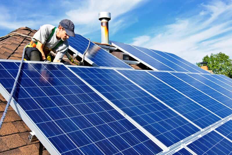 A man installing solar panels on a roof for renewable energy.