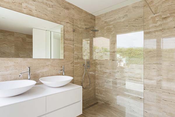 A bathroom with a glass shower and two sinks featuring slab shower walls.