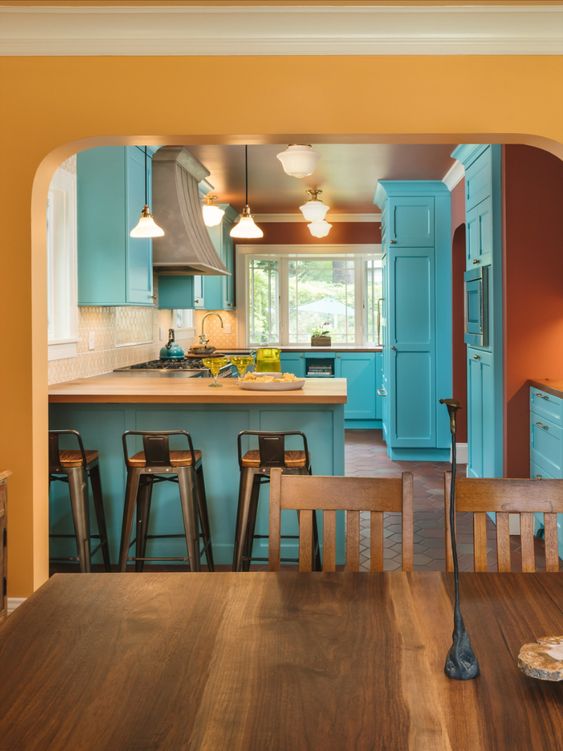 A kitchen with turquoise cabinets and a wooden table.
