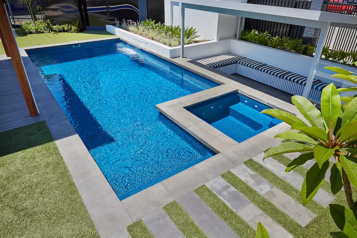 A modern swimming pool transformed into an oasis in a backyard.