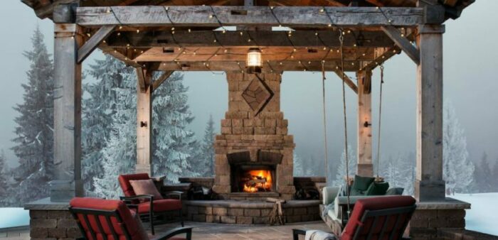 A snow-covered gazebo with chairs and an outdoor fireplace.