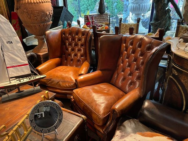 A pair of brown leather living room accent chairs in a store.