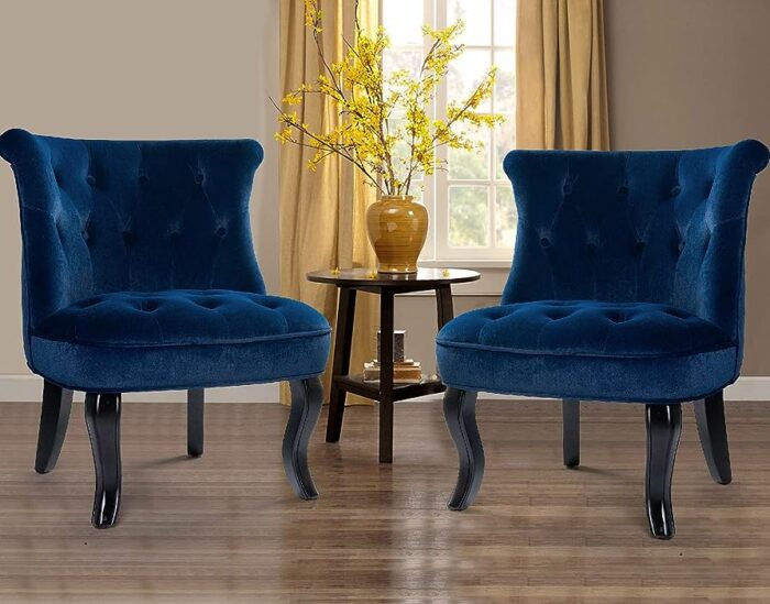 Two blue velvet accent chairs in front of a living room window.