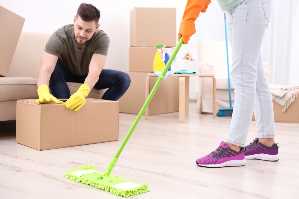 A couple providing cleaning service by mopping a room.