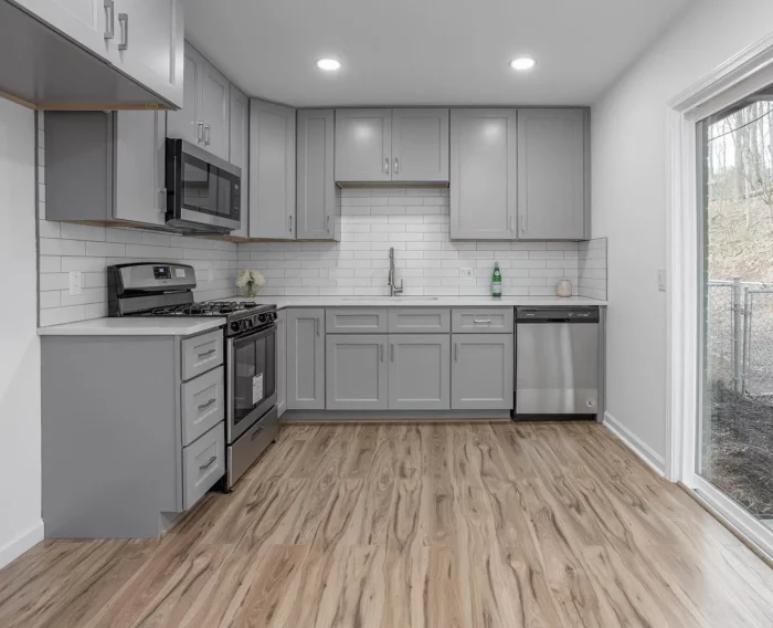A gray kitchen with hardwood floors and light gray kitchen cabinets.
