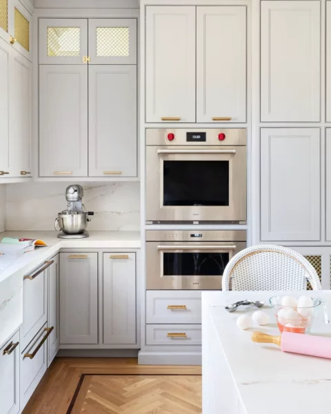 A kitchen with light gray cabinets and gold accents.