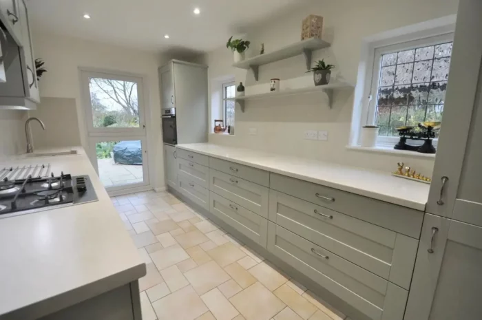 A light gray kitchen with grey cabinets and tiled floors.