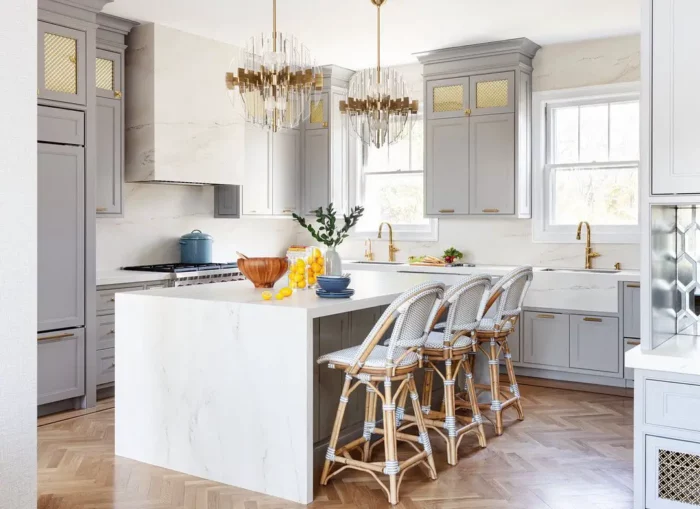 A light gray kitchen with cabinets and a marble island.