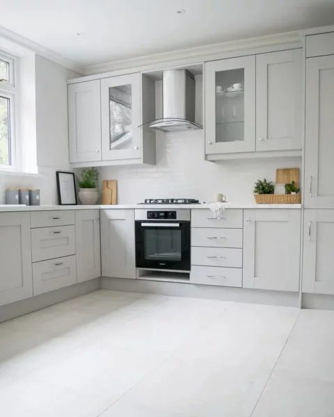 A kitchen with light gray cabinets and a tiled floor.