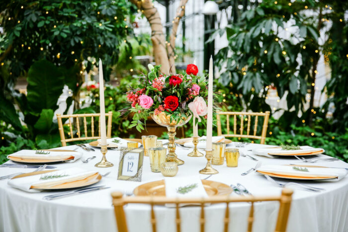 A gold and white table setting with flowers and greenery for restaurant design ideas.