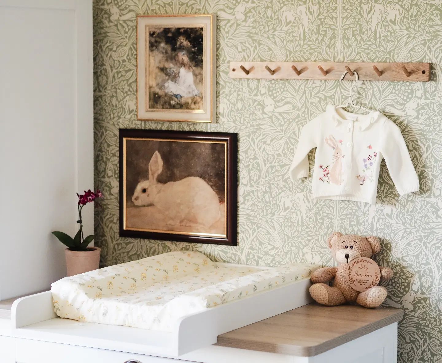A sage green nursery with framed pictures.