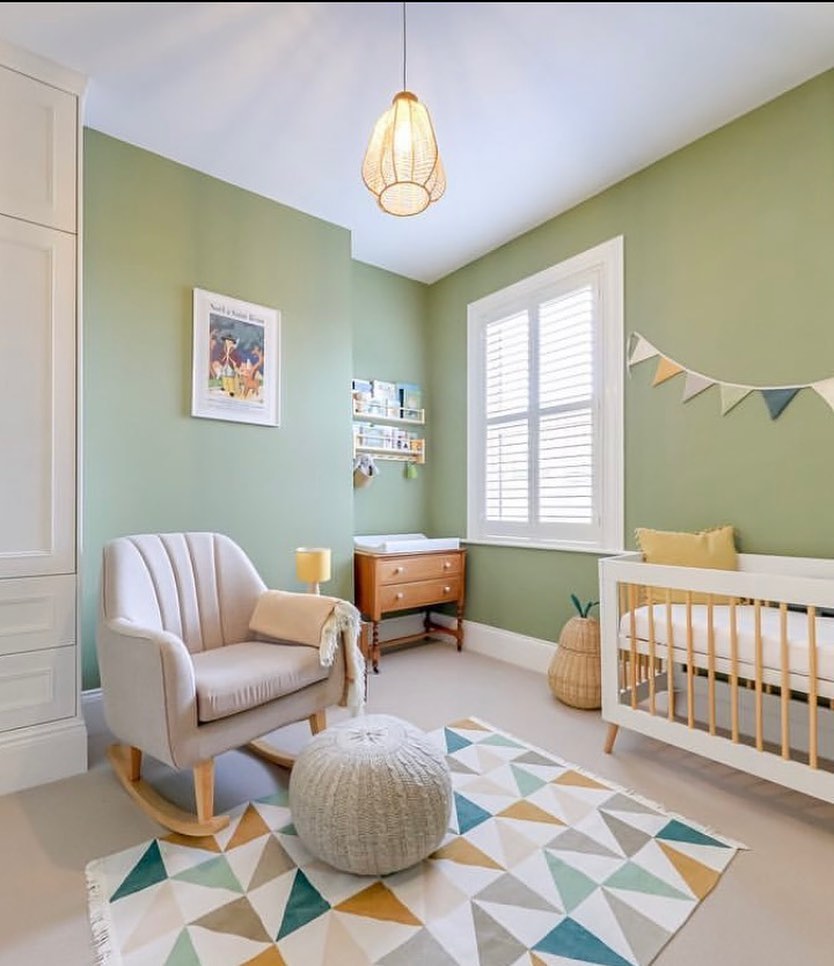 A sage green nursery with furniture.